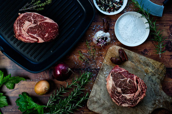 Prepping steak and onions for an electric grill or gas grill cooked meal with rosemary, onions, dates, and kosher salt for seasoning.