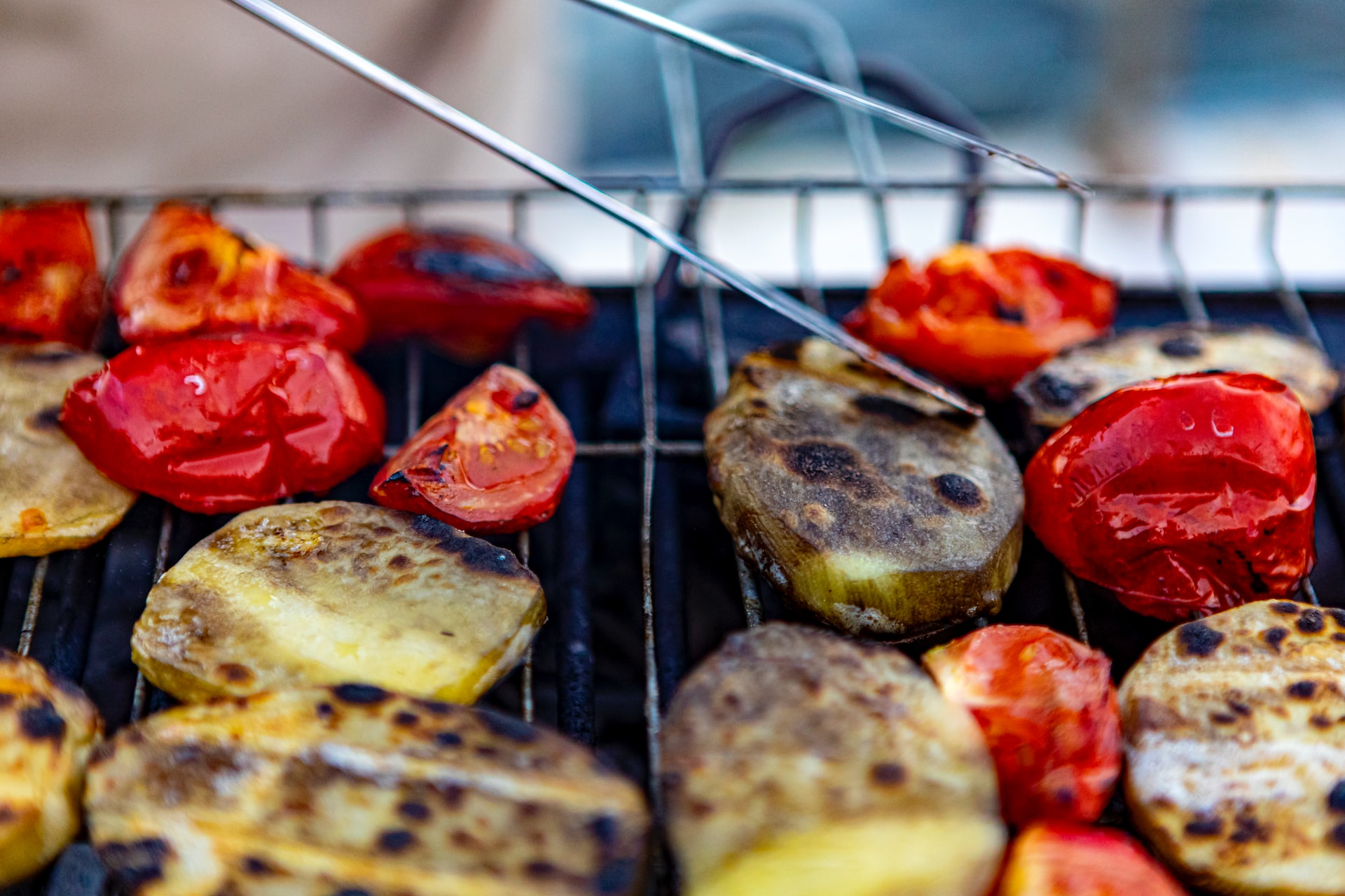 Close-up grill shot of plump red tomatoes and potatoes with char