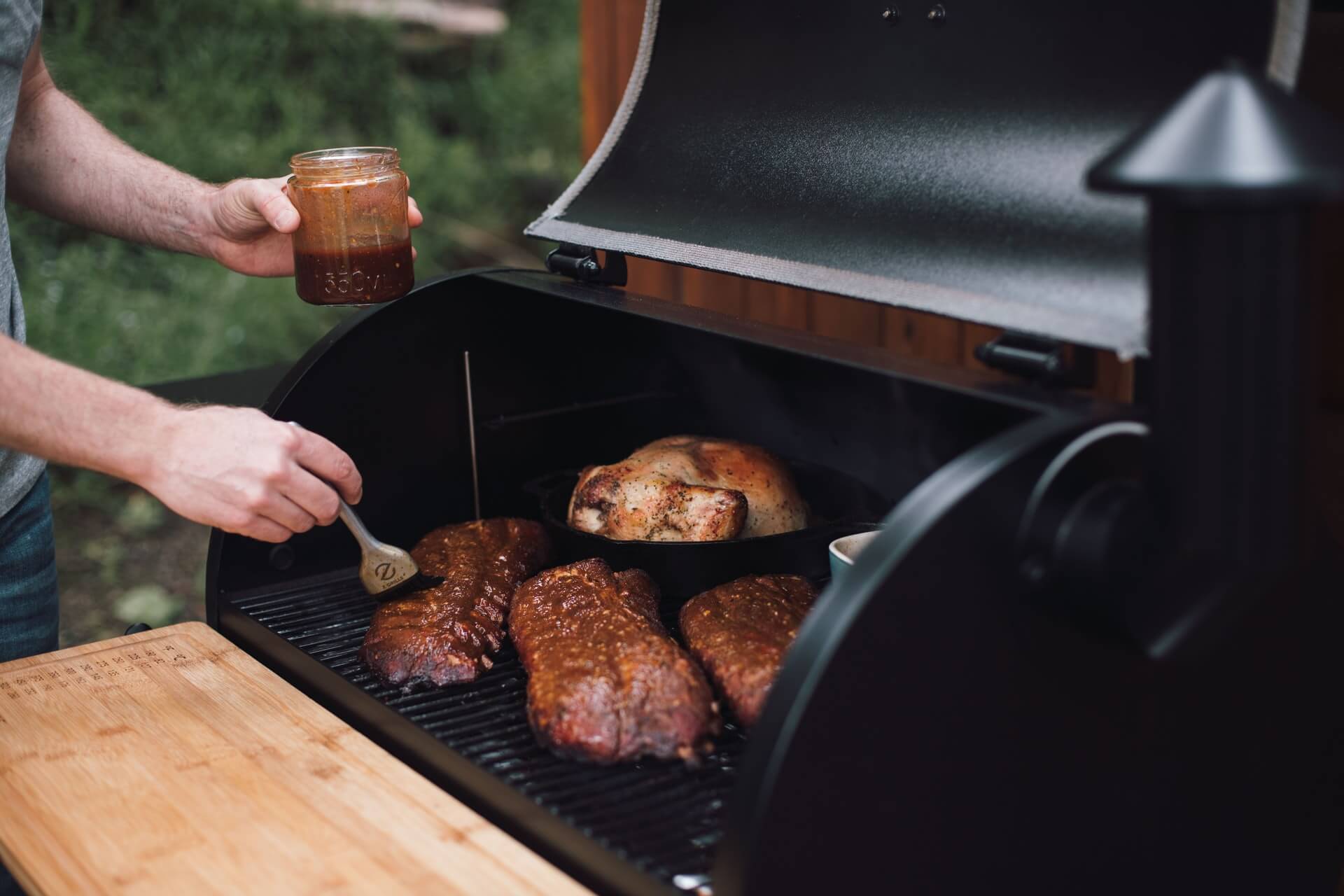 Man brushing meat with sauce on a grill