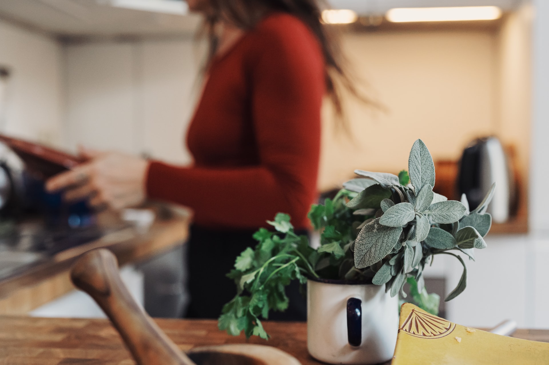 Image of a person with fresh herbs in the foreground prepping a meal for outdoor cooking