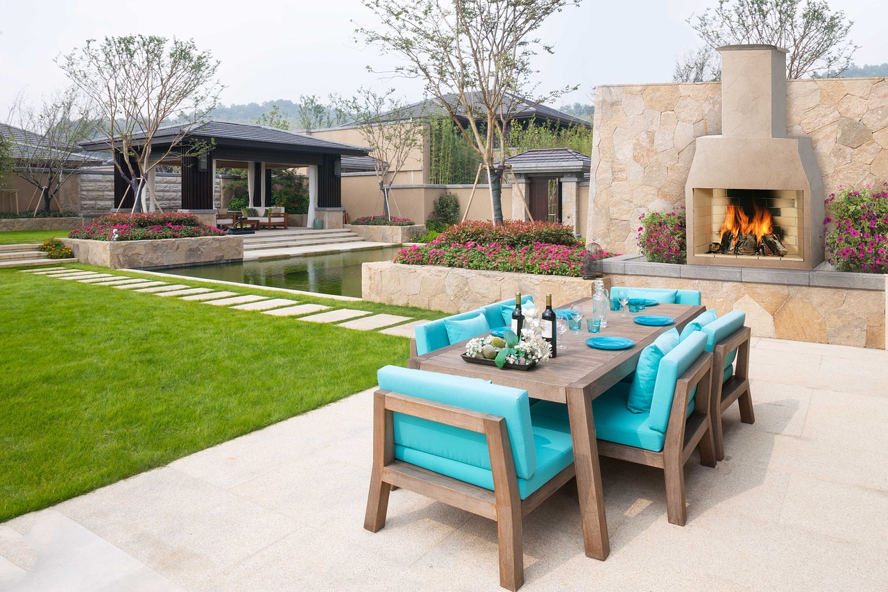 outdoor fireplace near table with blue chairs
