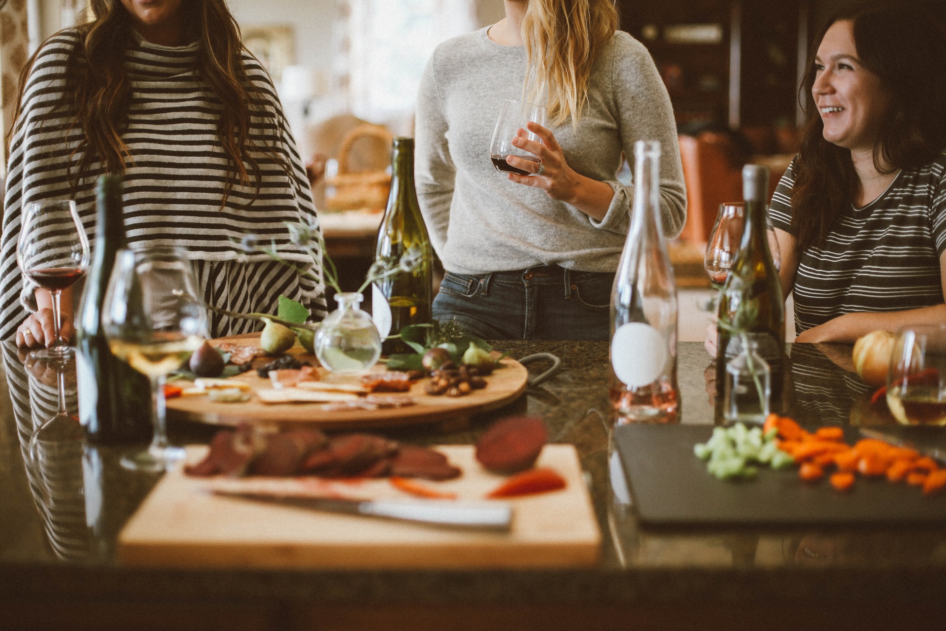 Smiling women holds wine glass with two friends in an outdoor dining area