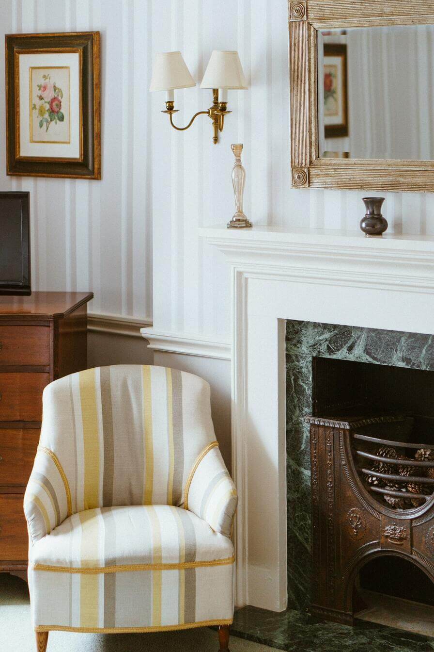 Striped arm chair beside classic fireplace